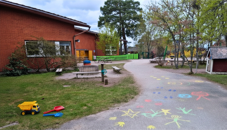 Förskolegård med lekredskap, målade spår på marken och grönska – en trygg plats för fantasi, rörelse och lekglädje.