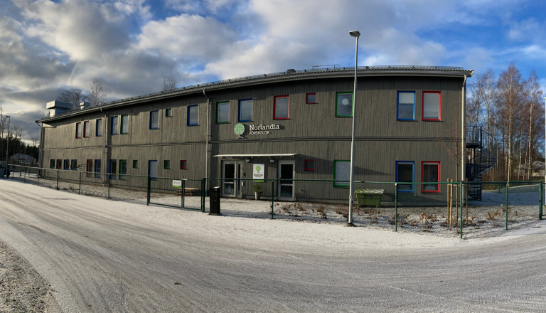 Tvåvånings förskola i trä med färgglada fönster i vintrig miljö – en trygg plats för lek, lärande, nyfikenhet och gemenskap.