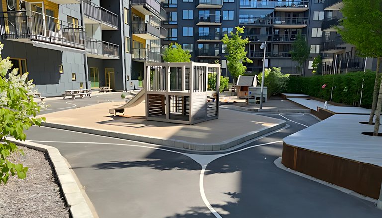 Förskolegård i innergårdsmiljö med lekställning, rutschkanor, cykelvägar och omgivande flerbostadshus.