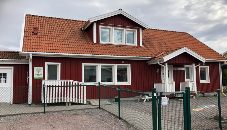 Röd träförskola med vita detaljer och staket – en hemtrevlig miljö där barn möts av trygghet, lek och lärande varje dag.