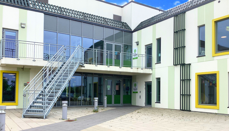 Modern förskolebyggnad med glaspartier, färggranna detaljer och entréplan – en trygg plats för lärande och lek.