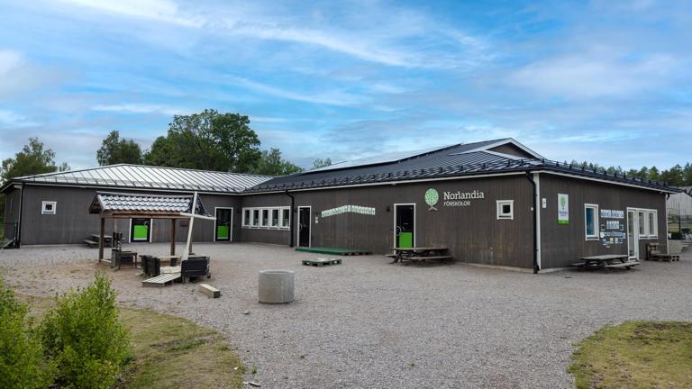 Förskolegård med träbyggnad, tipi-tält och skog i bakgrunden – en plats där barn får utforska, leka och lära utomhus.
