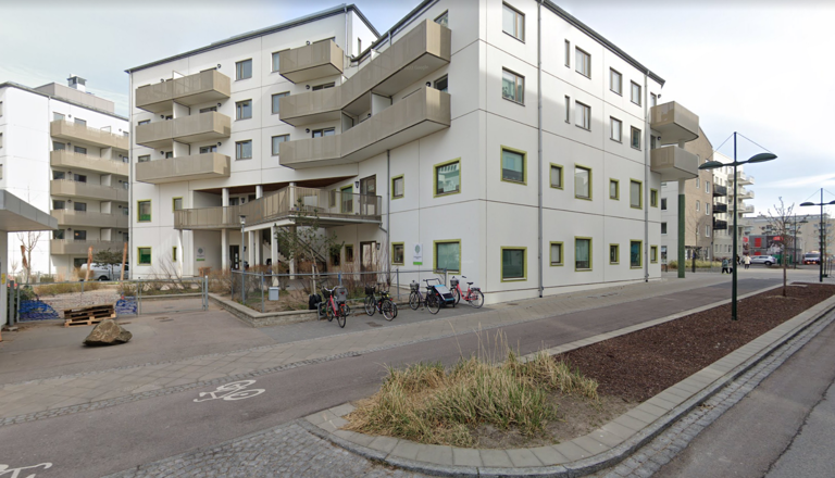 Modern förskola i stadsmiljö med entré i bottenplan och cyklar utanför – en trygg plats för lek, glädje och gemenskap.