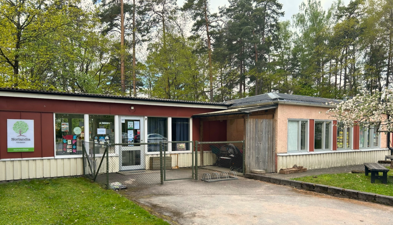 Låg förskolebyggnad med entré, Norlandia-skylt och cykelställ – en trygg plats för lek, gemenskap, nyfikenhet och lärande.